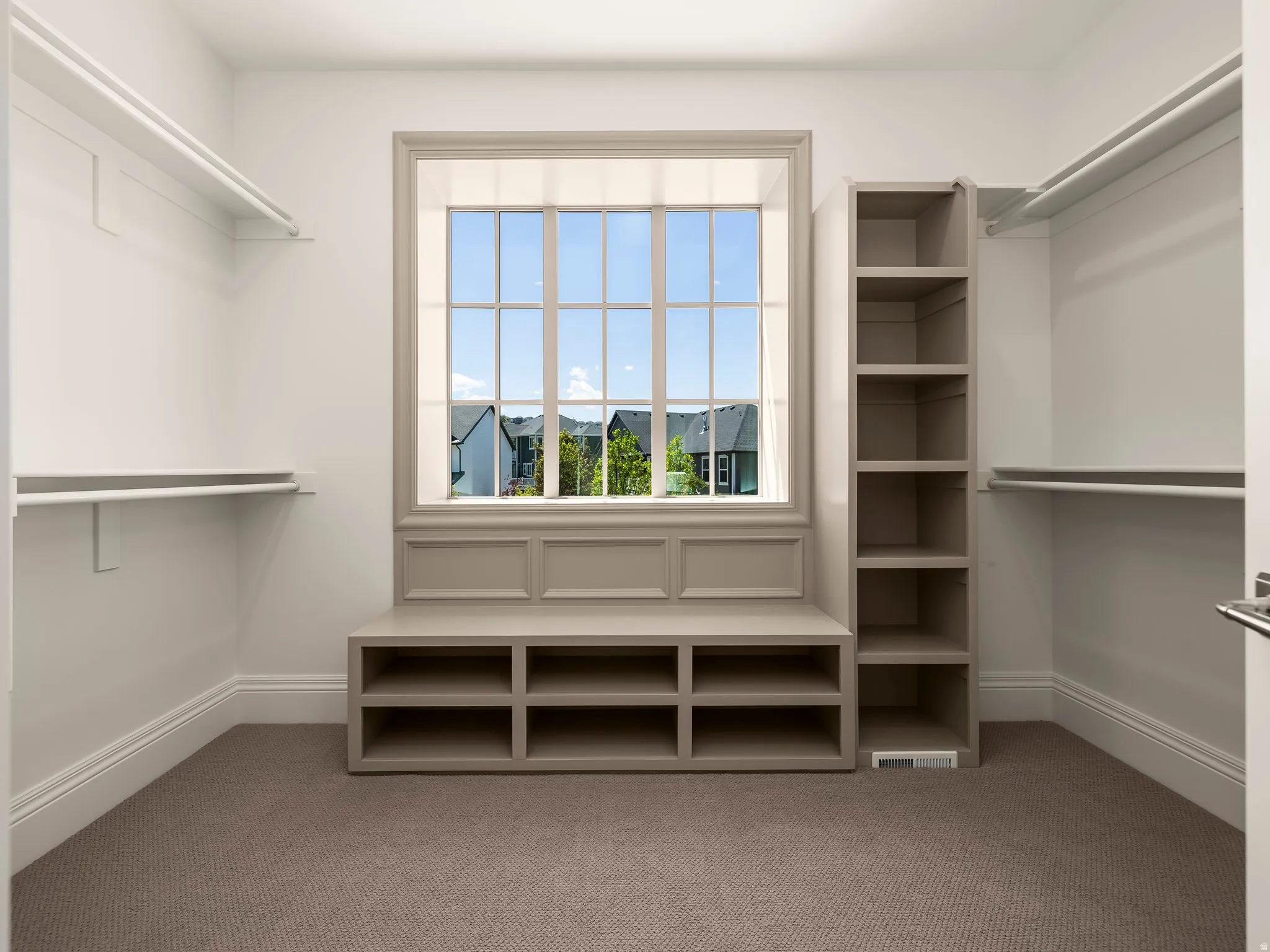 Custom closet system featuring built-in shelving, hanging rods, and a window seat with integrated storage