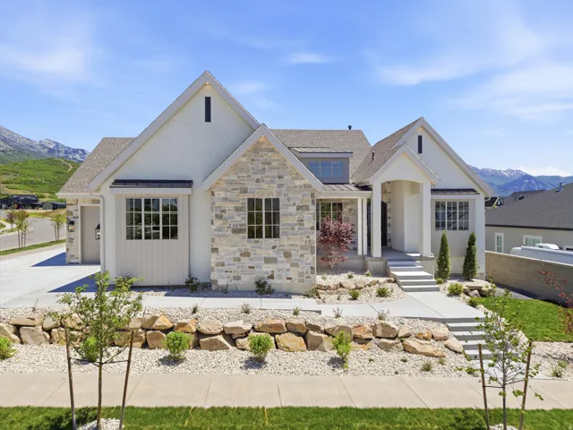 White stucco and natural stone facade with multiple gables and a covered entry