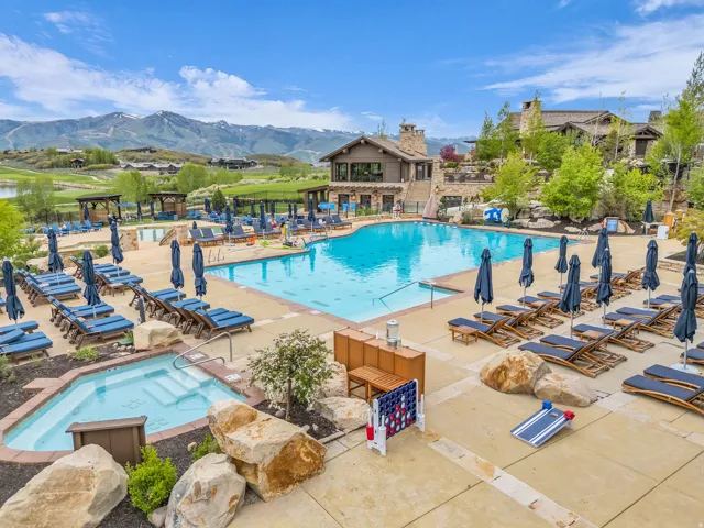 Expansive outdoor pool area featuring a large swimming pool, an integrated spa, and extensive surrounding patio space with lounge seating