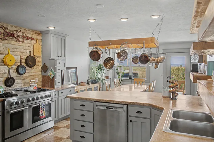Spacious kitchen featuring an expansive island with a double basin sink, stainless steel appliances, and checkerboard floor tiles