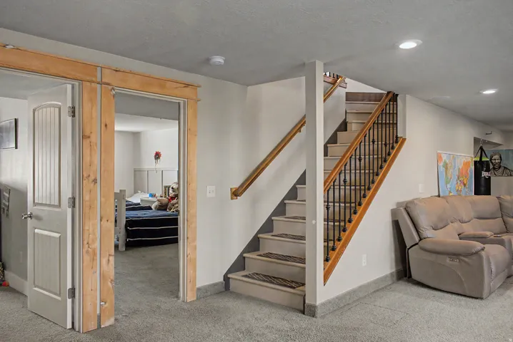 Carpeted staircase with black wrought iron spindles and wood handrails