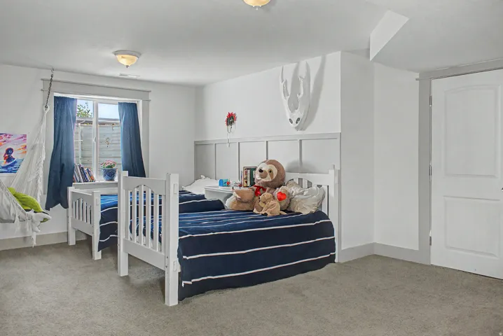 Carpeted room with a paneled accent wall, a window, and a white interior door