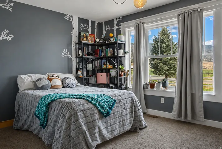 Bedroom featuring a large window, white trim, and a decorative wall