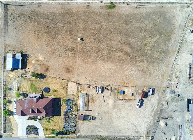 Extensive property featuring a primary residence with a red tile roof, a circular driveway, and a large, undeveloped land parcel