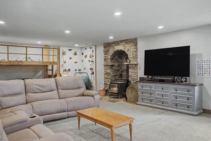 Recreational space featuring a stone archway with a wood-burning stove, recessed lighting, and a built-in climbing wall