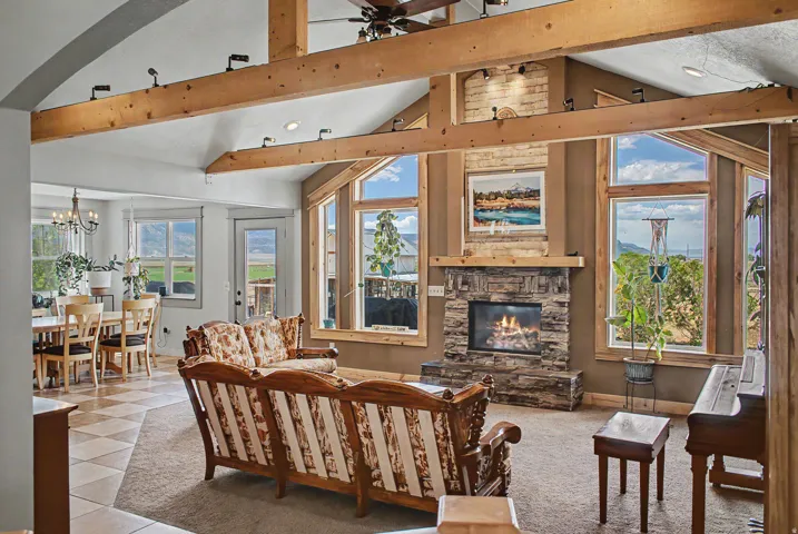 Vaulted ceilings with exposed wood beams define this living area, featuring a stone-clad fireplace with a wood mantel