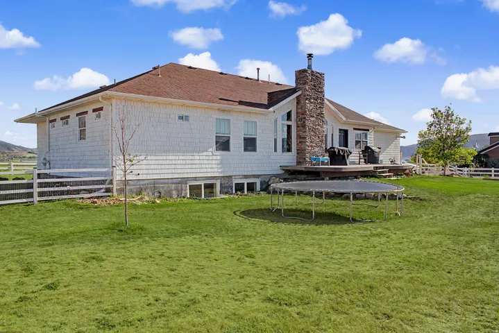 Expansive rear exterior featuring white shingle siding and a prominent stone chimney