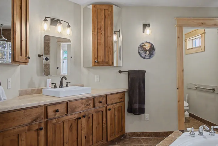 Spacious vanity featuring a rectangular vessel sink, dark bronze-finish faucet, and wood-finish cabinetry