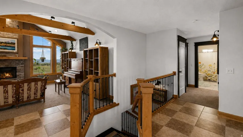 Vaulted ceilings with exposed timber beams define the living area, featuring a stone-faced fireplace and large picture windows