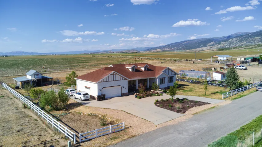 Contemporary ranch-style residence featuring an attached two-car garage, mature landscaping, and a fenced perimeter