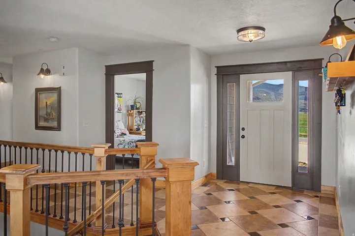 Entryway featuring a Craftsman-style front door with frosted glass sidelights, patterned tile flooring, a custom wood staircase with metal balusters, and a semi-flush mount ceiling light