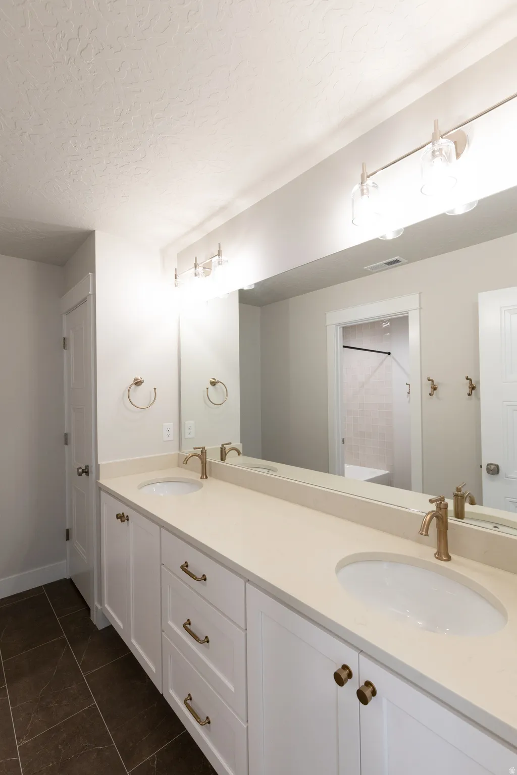 Dual sink vanity with white cabinetry, light-toned countertop, and bronze-finish hardware