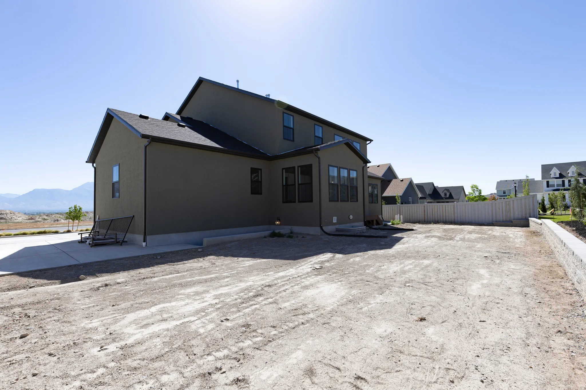 Expansive rear lot featuring a concrete patio, retaining wall, and full wooden perimeter fencing