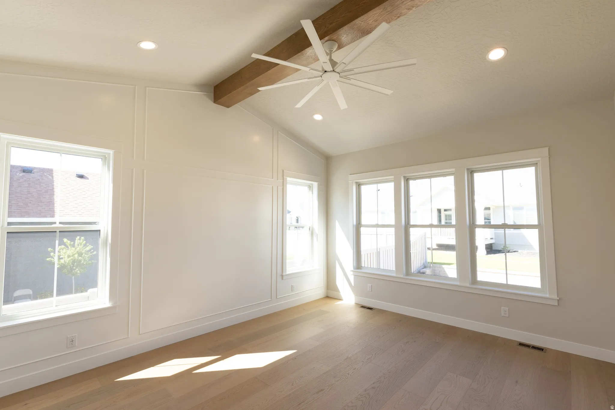Vaulted ceiling featuring a wood-finish beam and a modern ceiling fan