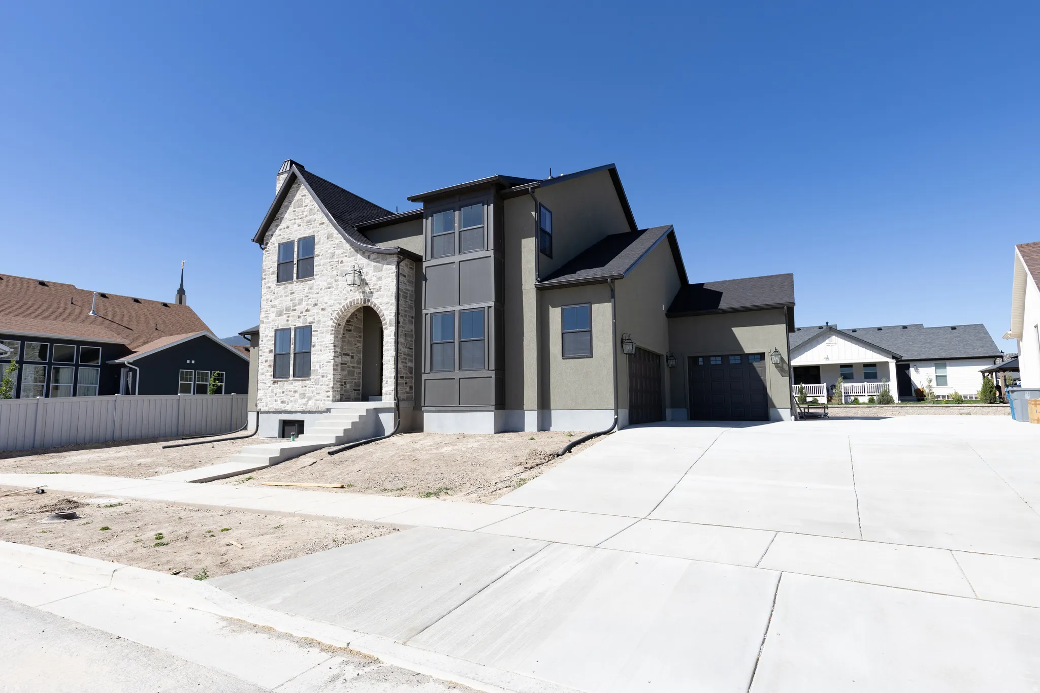 Newly constructed residence featuring a stone façade, arched entry, multi-pane windows, and a two-car garage