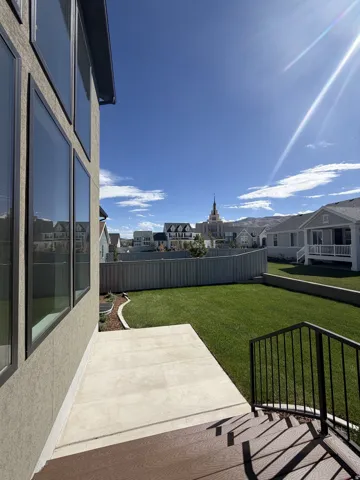 Expansive backyard with a manicured lawn, concrete patio, and composite deck with metal railing