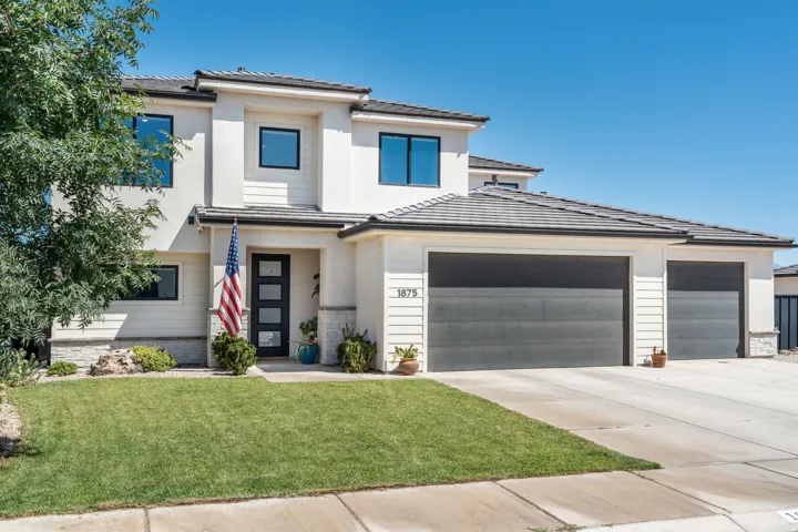 Contemporary stucco exterior featuring a two-car garage, dark-framed windows, and a modern entry door with vertical glass inserts