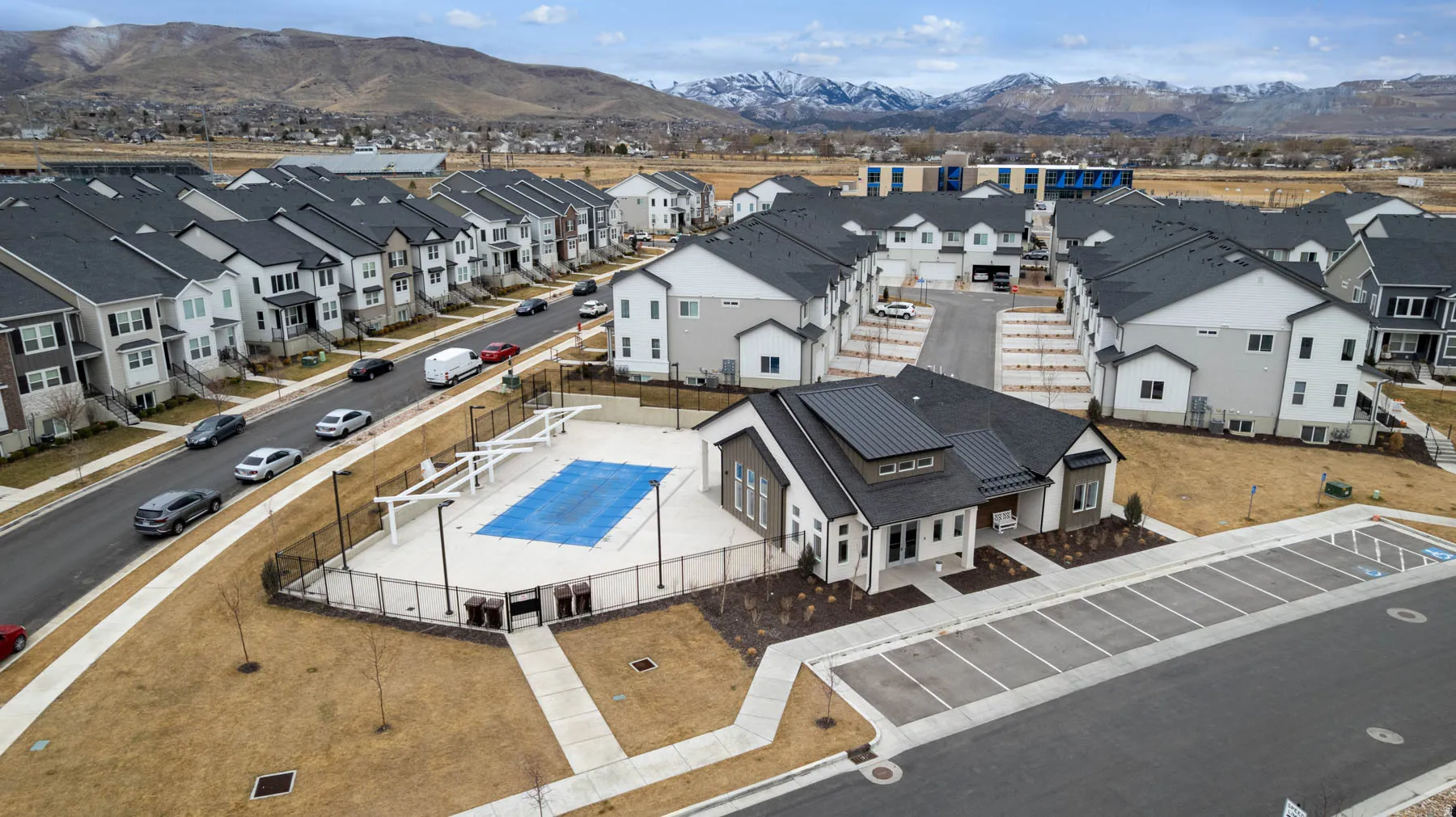 Modern residential development featuring a community pool with an expansive concrete deck, fenced perimeter, and nearby structured parking