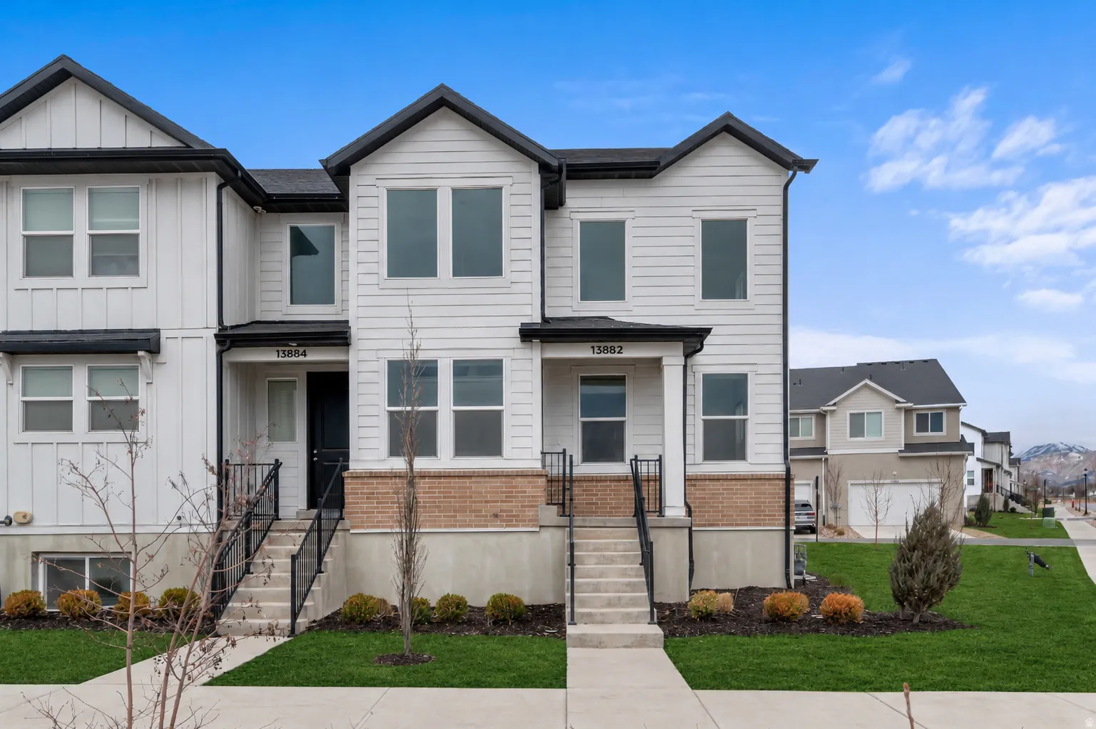 Modern townhome exterior featuring white siding and black trim accents