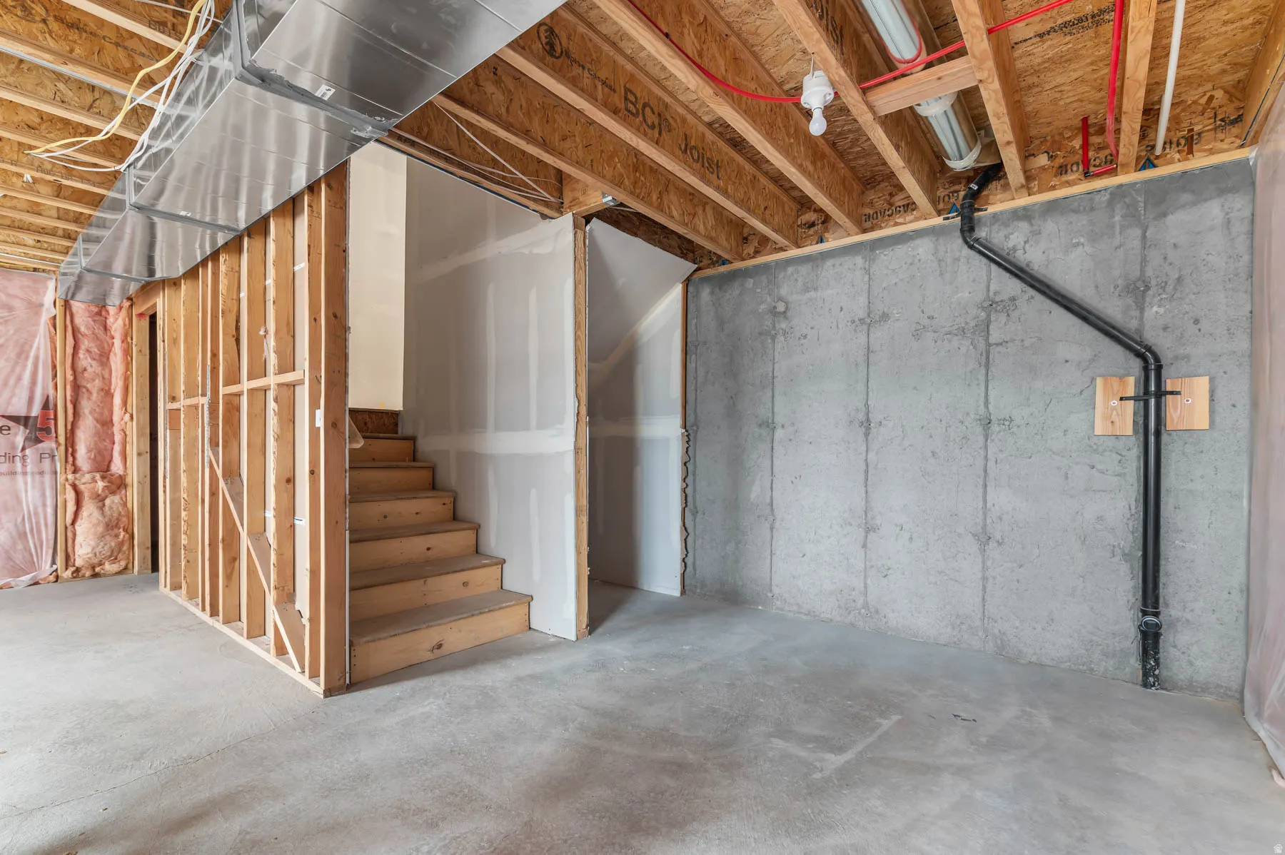 Unfinished basement area featuring exposed wood joists, concrete foundation walls, and a concrete floor
