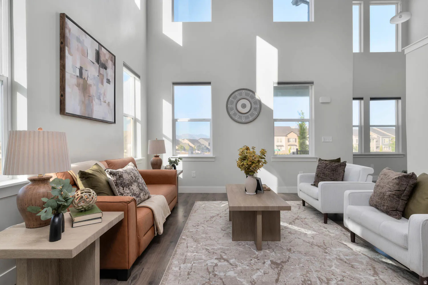 Living area with soaring ceilings and multiple windows, dark wood-finish flooring, and light wall finishes