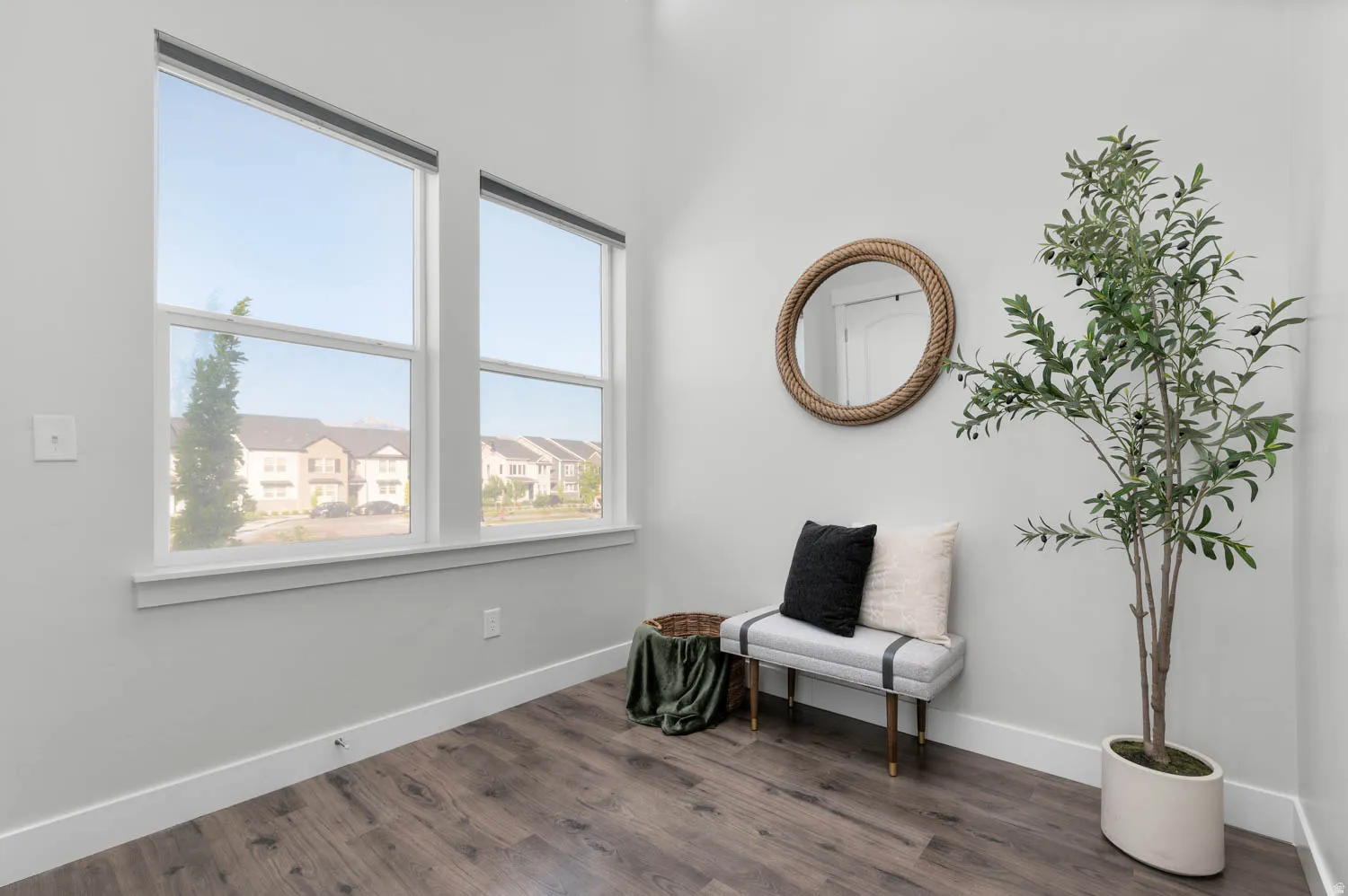 Bright room featuring a pair of tall windows with white trim, wood-finish flooring, and light gray wall paint