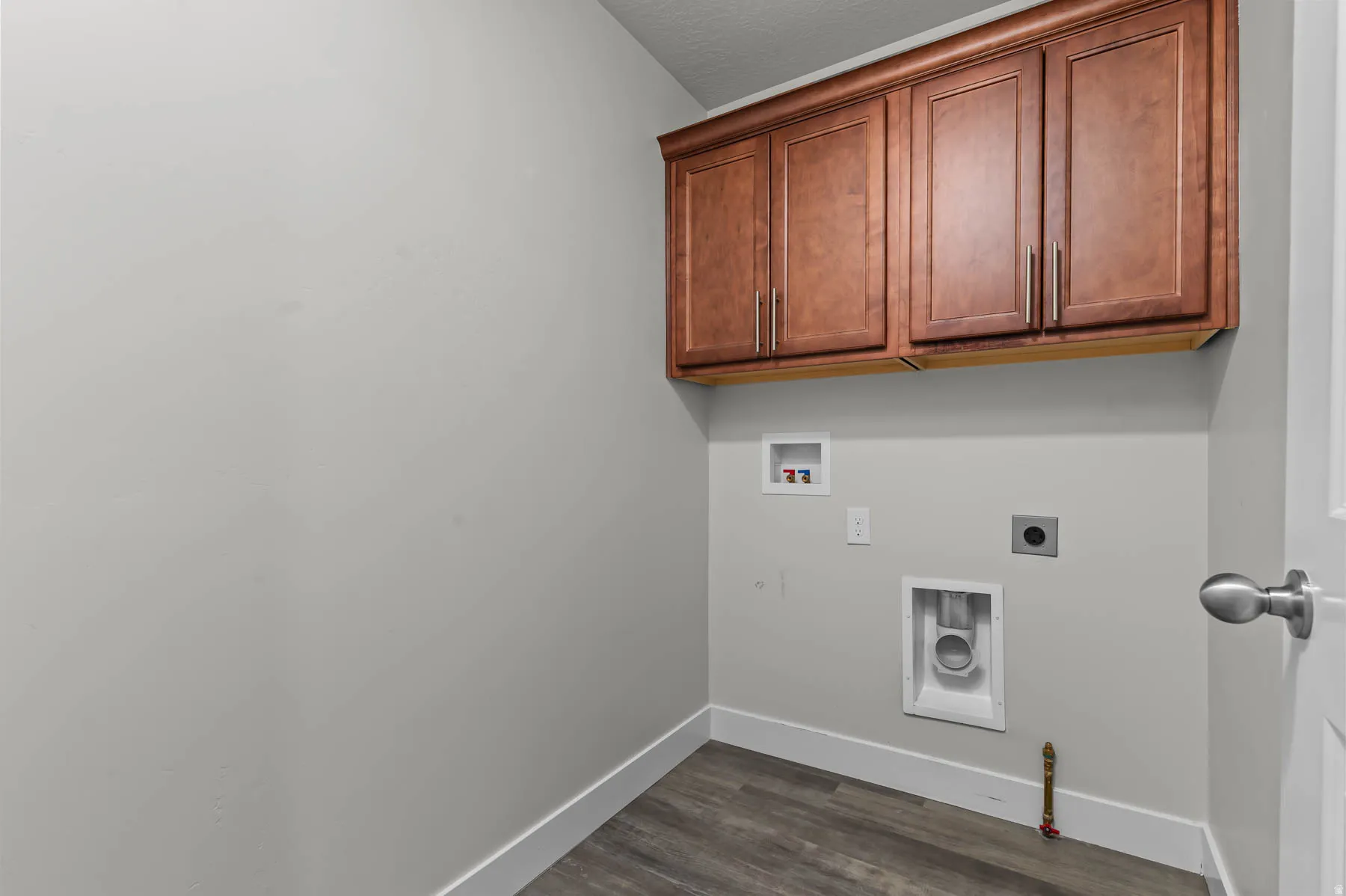 Laundry area featuring wood-finish flooring, white baseboards, and light gray walls