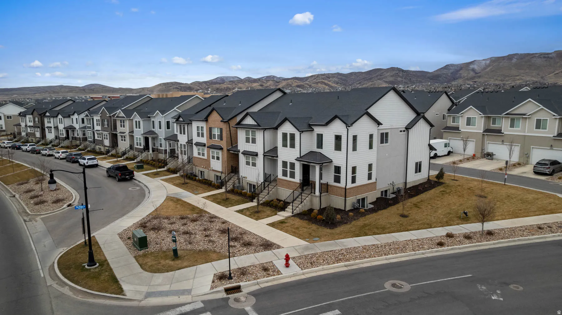 Contemporary townhome exteriors featuring varied siding, dark shingle roofing, and integrated garages
