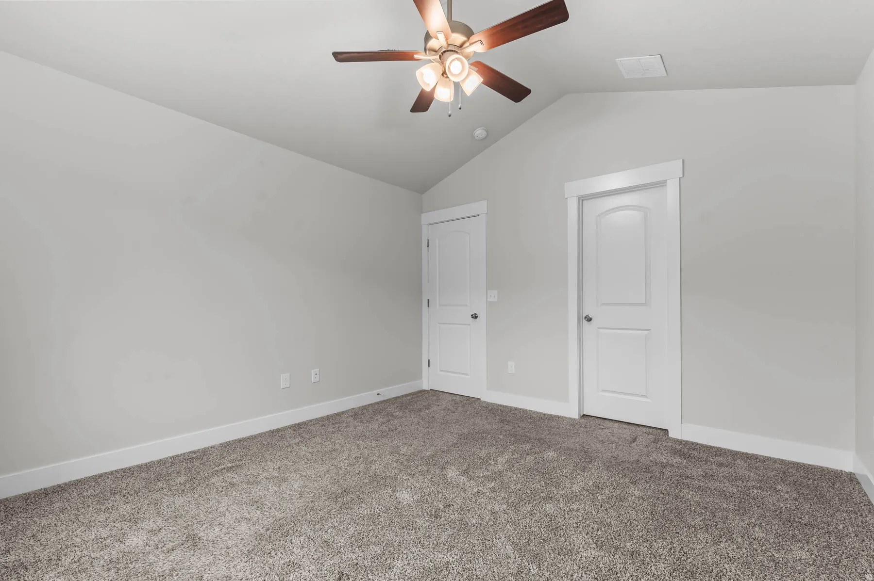 Room featuring vaulted ceilings, neutral-toned walls, and plush carpeting