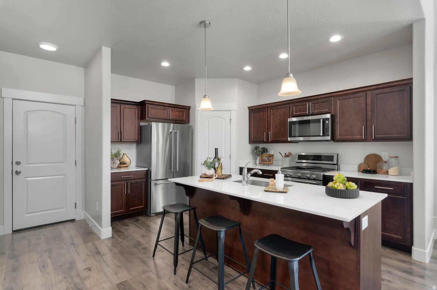 Kitchen featuring dark wood-finish cabinetry, stainless steel appliances, and wood-finish flooring