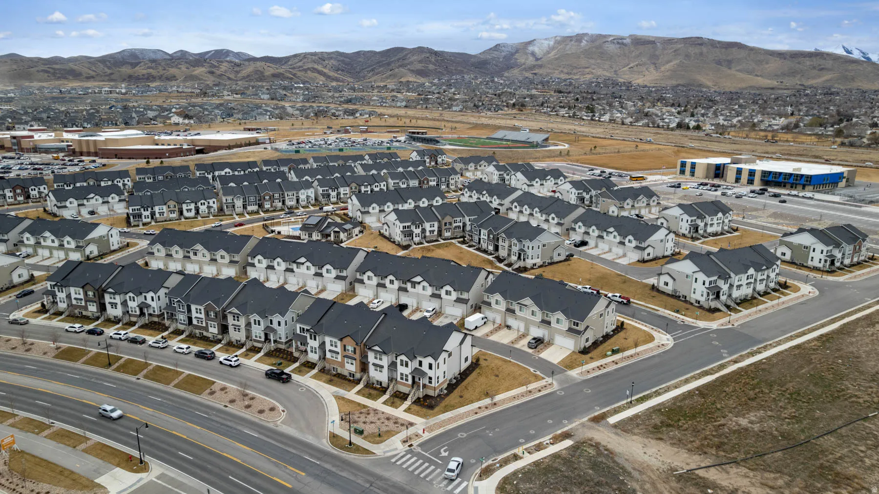 Newly developed residential community featuring rows of modern homes with dark roofs and light-colored facades