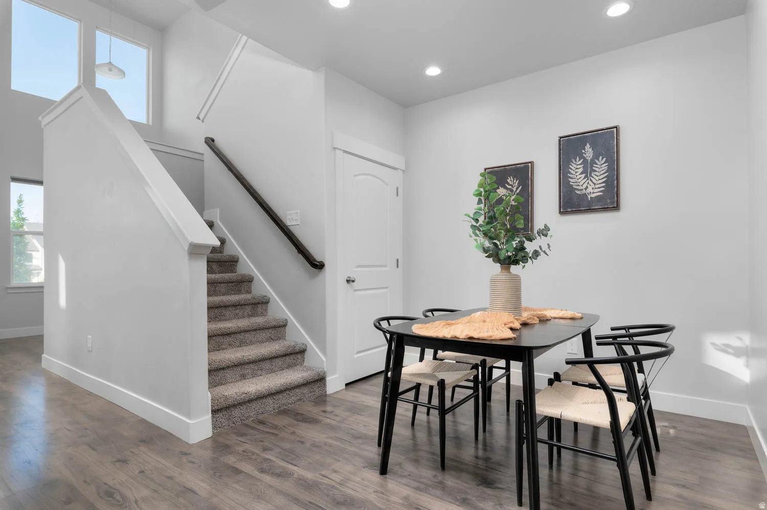 Open concept space featuring a carpeted staircase with a dark wood handrail, high ceilings, and recessed lighting