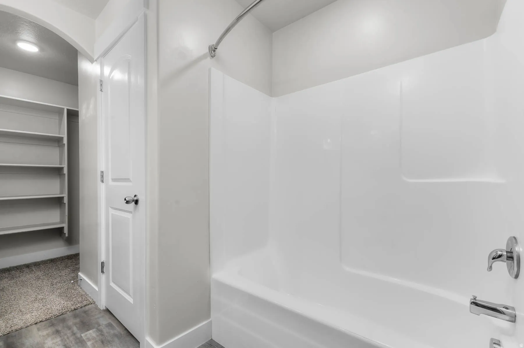 White bathtub with integrated shower, chrome fixtures, and a curved shower rod