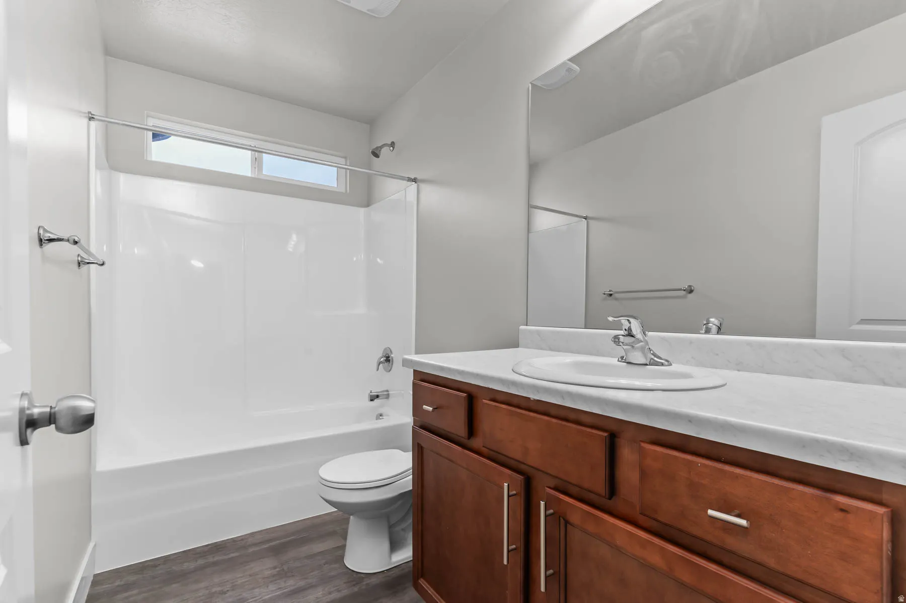 Full bathroom featuring a wood-finish vanity with an integrated sink, polished chrome faucet, and a large wall-mounted mirror