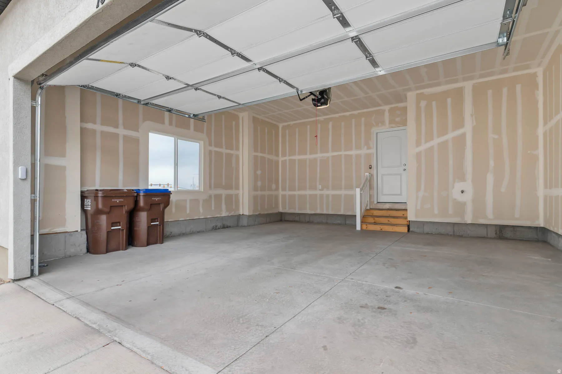Two-car garage featuring a concrete floor, an overhead door with opener, and a window for natural illumination