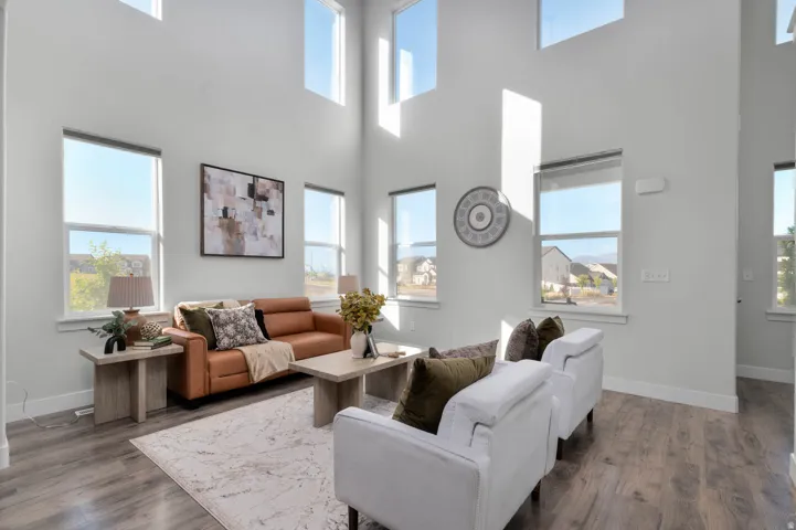 Vaulted ceilings with high windows, light gray wall tones, wood-finish flooring, and multiple large windows
