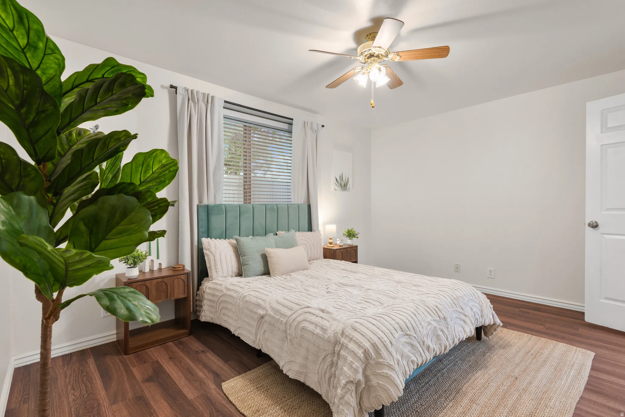 Bright Primary Suite featuring wood-finish flooring, a ceiling fan with integrated lighting, and a window fitted with blinds