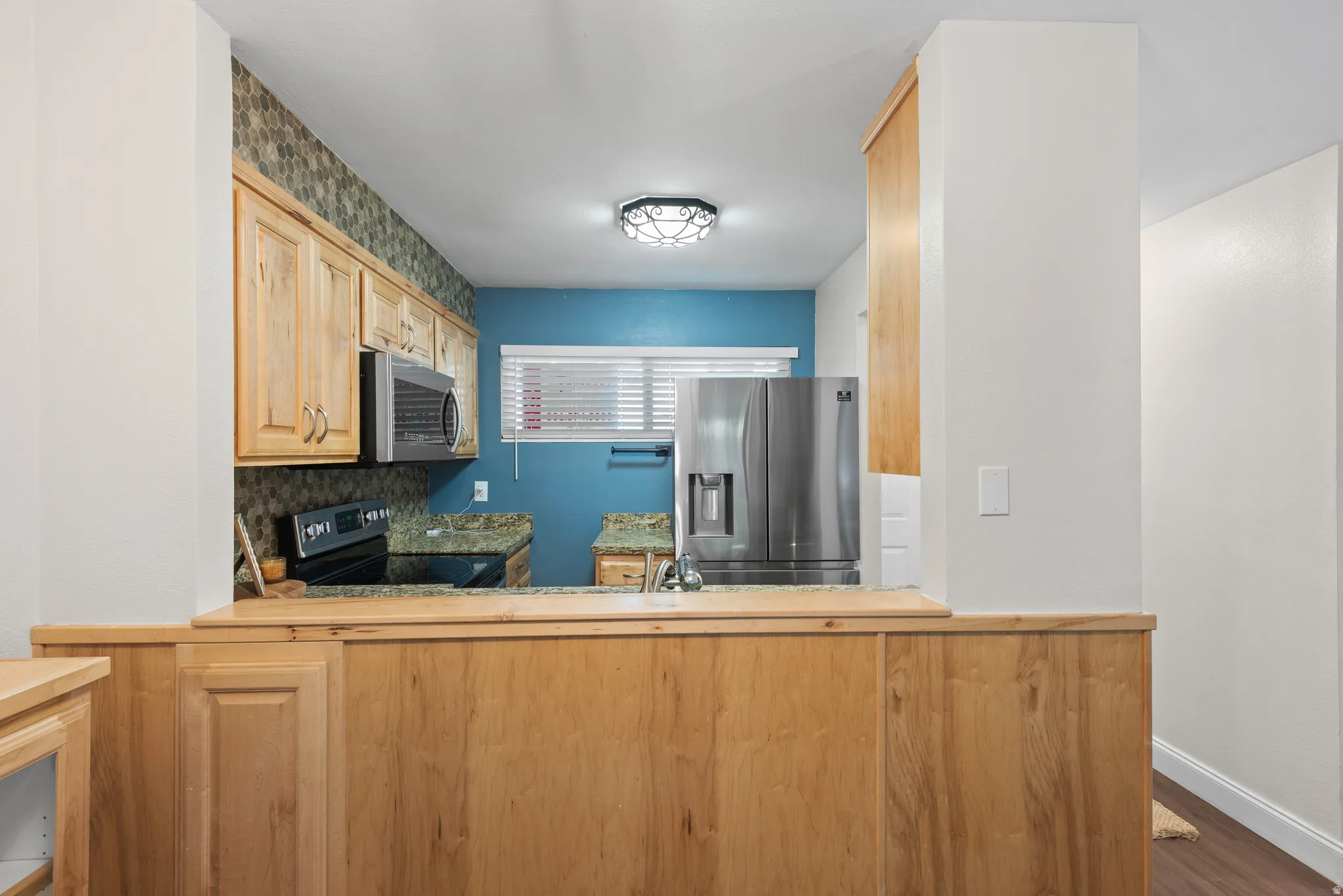 Kitchen featuring a stainless steel refrigerator, built-in microwave, and black electric range