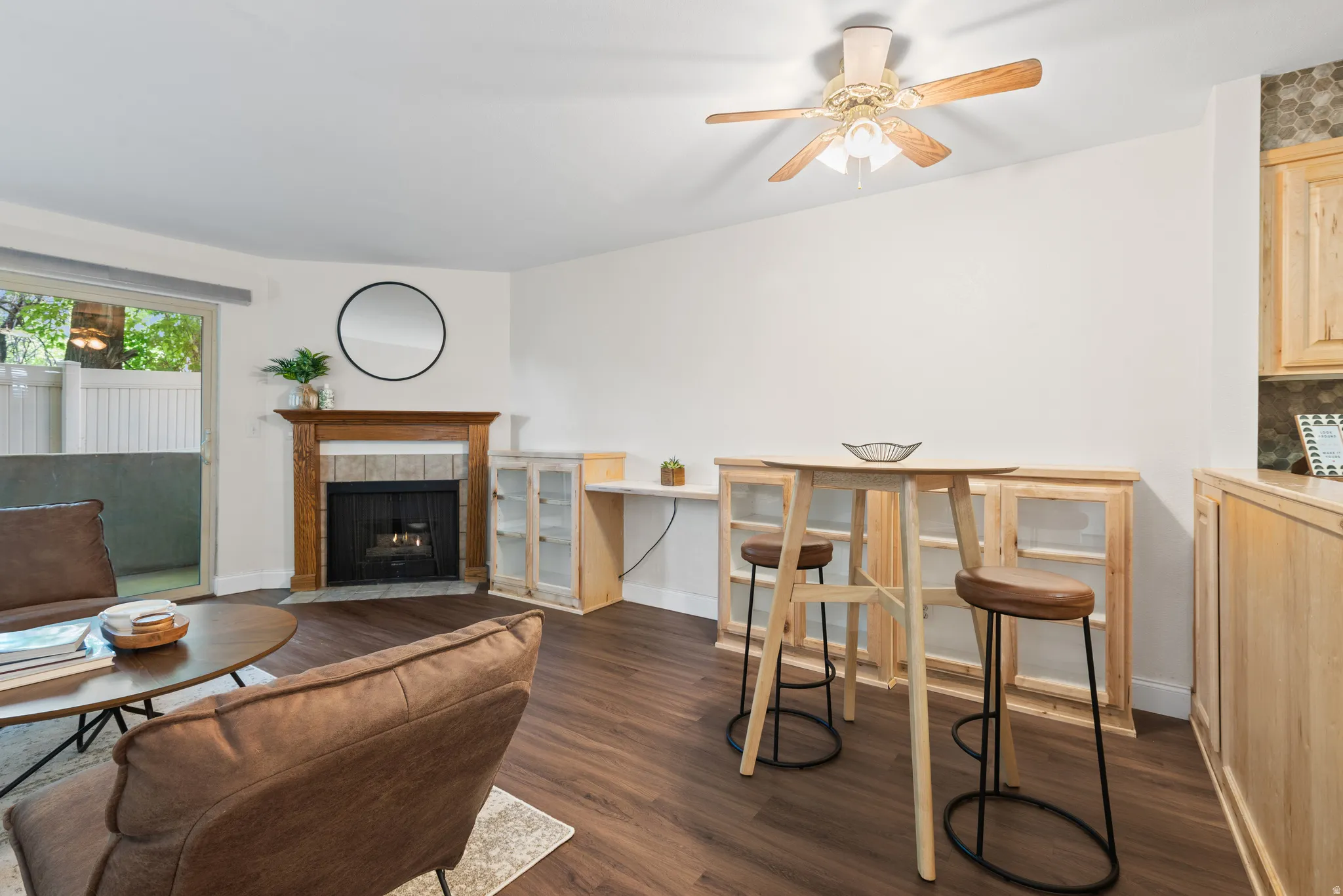 Living area featuring wood-finish flooring, a fireplace with a wood mantel and tile surround, and a sliding glass door