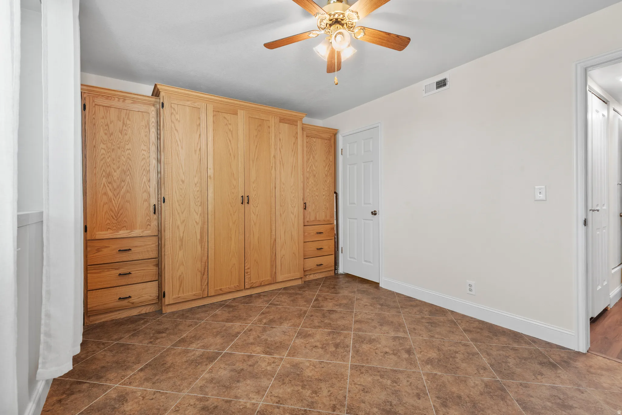 Room with extensive built-in wooden cabinetry featuring multiple doors and drawers