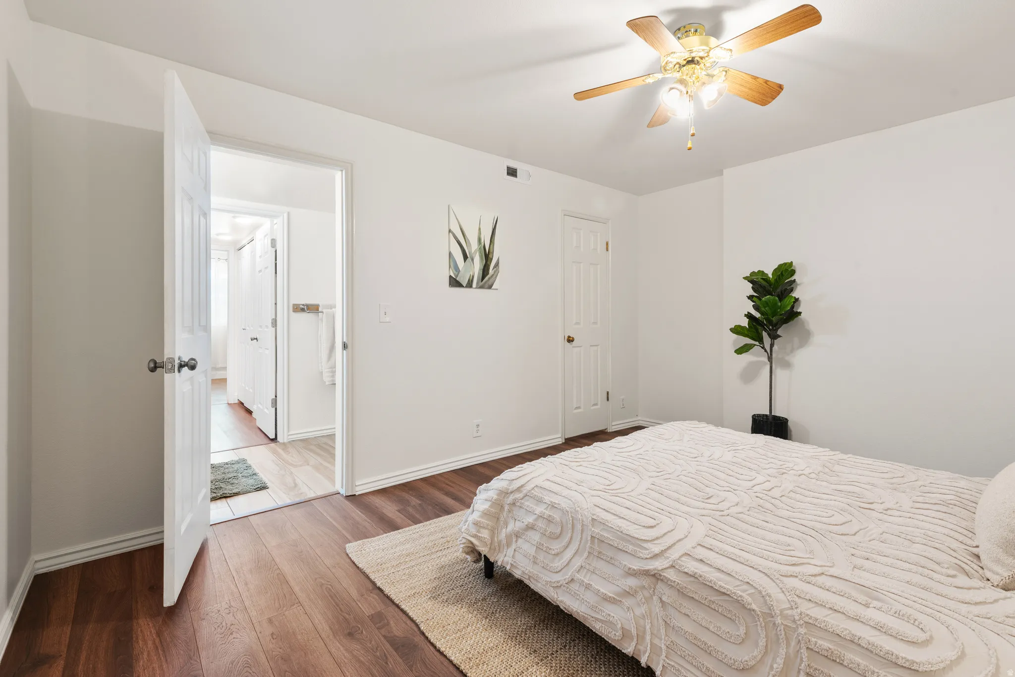 Spacious Primary Suite featuring wood-finish flooring, white baseboards, and a paddle ceiling fan with integrated lighting