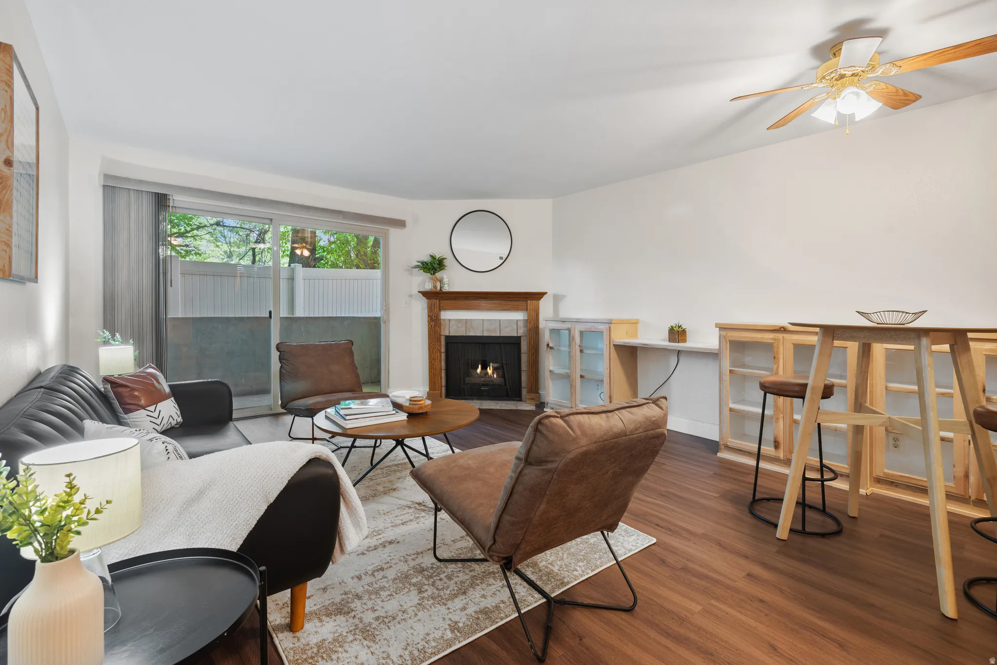 Living area featuring wood-finish flooring, a fireplace with a wood mantel, and sliding glass doors opening to an outdoor space
