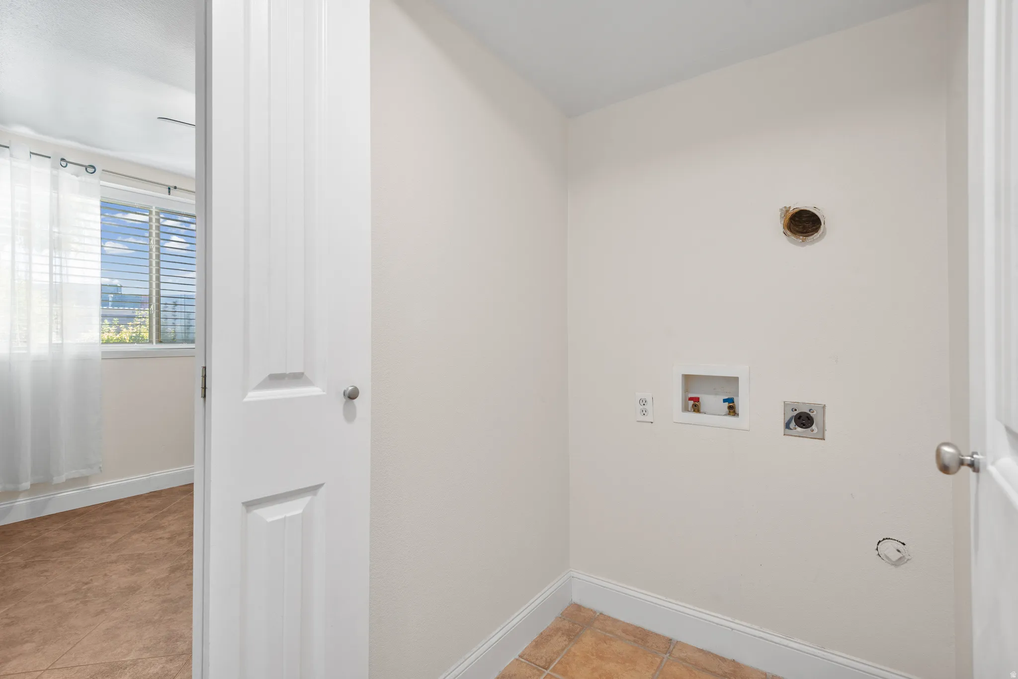 Dedicated laundry area featuring tile flooring, white walls, and hookups for appliances