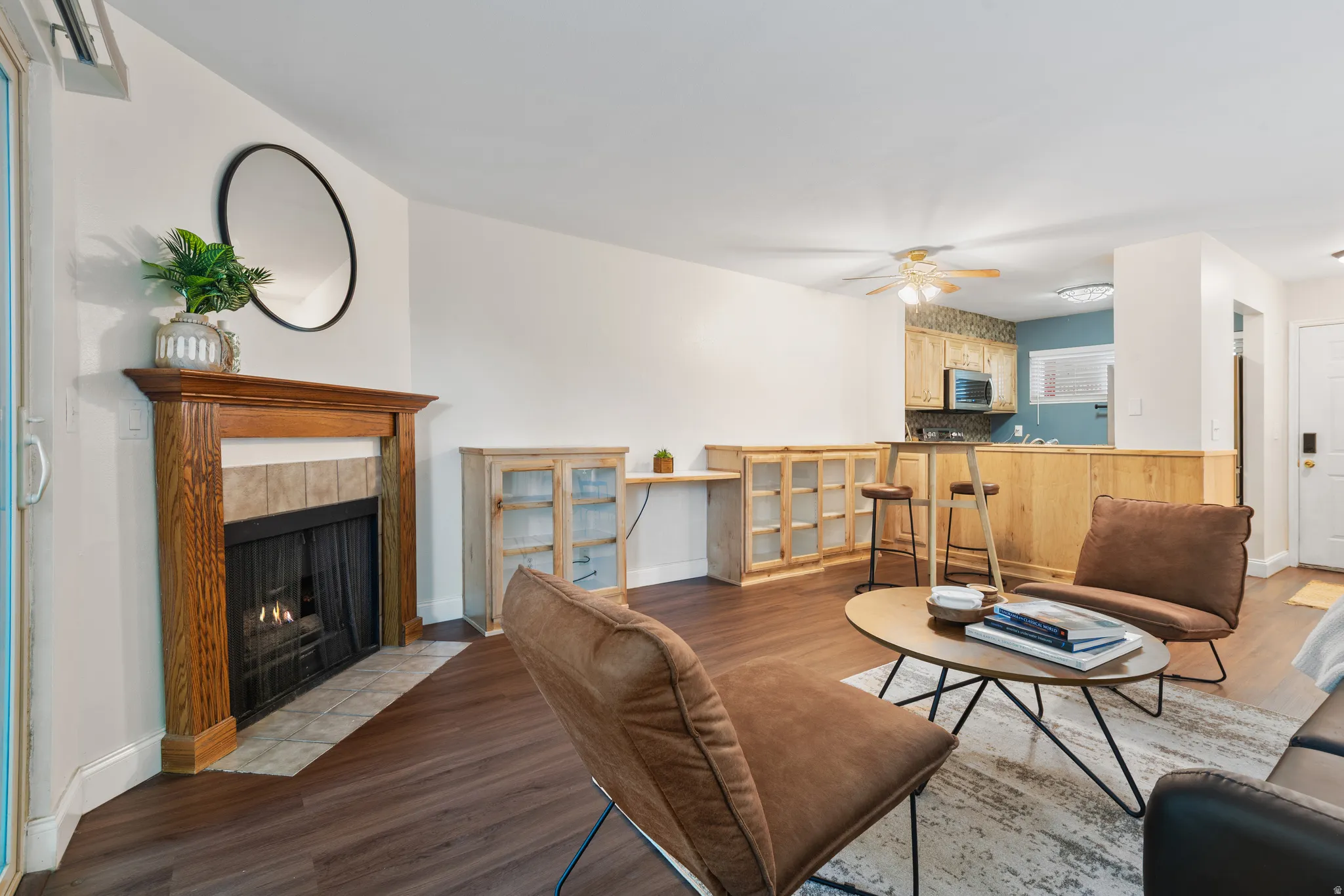 Living area featuring wood-finish flooring, a fireplace with a wood mantel, and built-in cabinetry