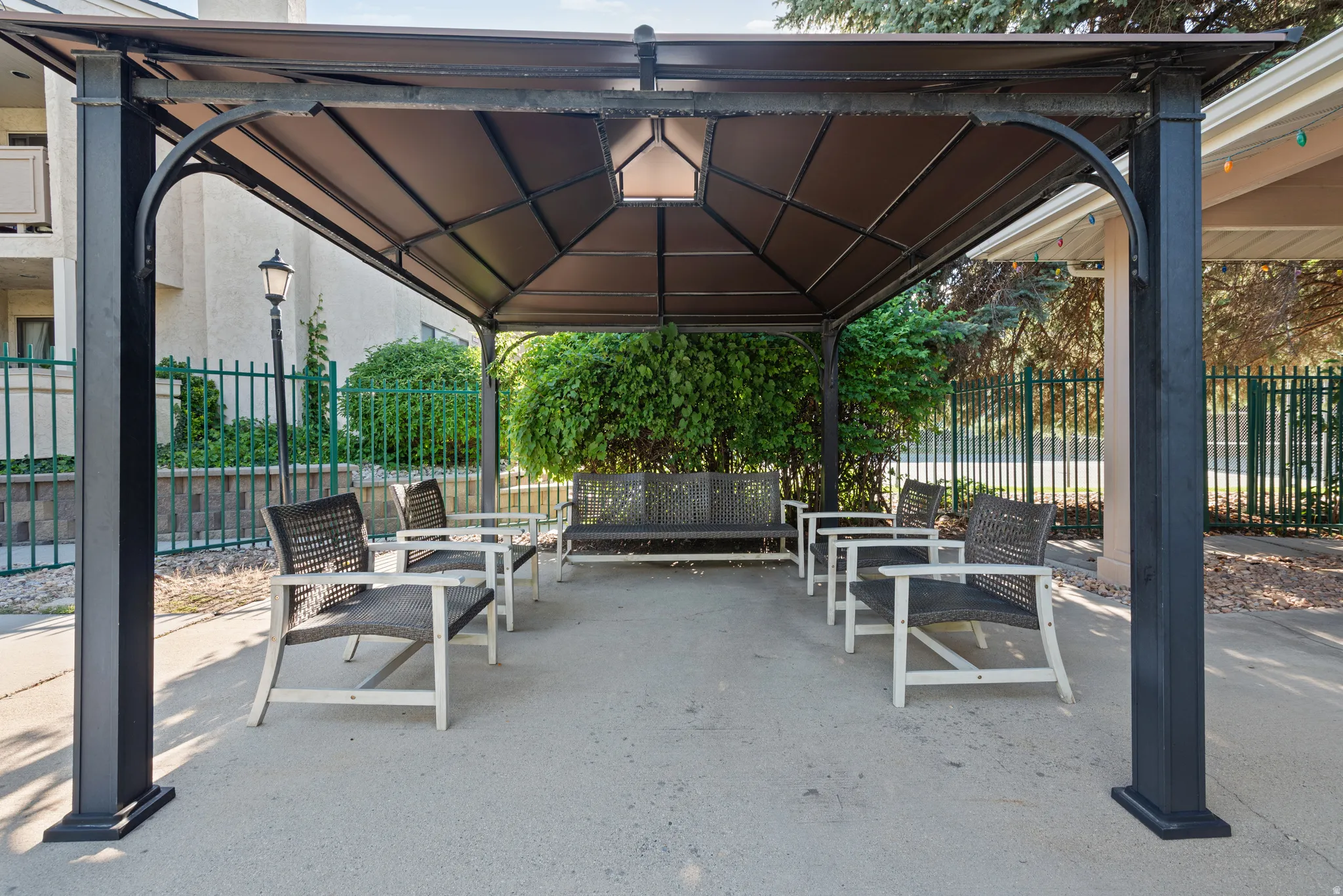 Metal gazebo structure with a fabric canopy and integrated ceiling light, situated on a concrete pad