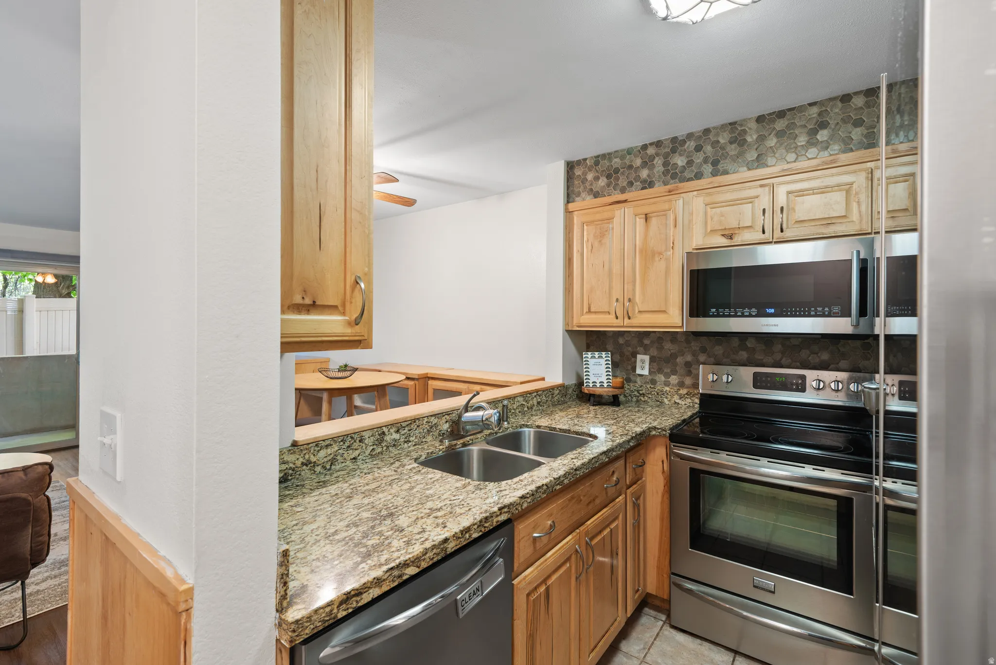 Kitchen featuring wood cabinetry, granite-style countertops, and a stone mosaic tile backsplash
