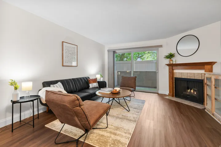 Living area featuring wood-finish flooring, a fireplace with a wood mantel and tile surround, and a sliding glass door