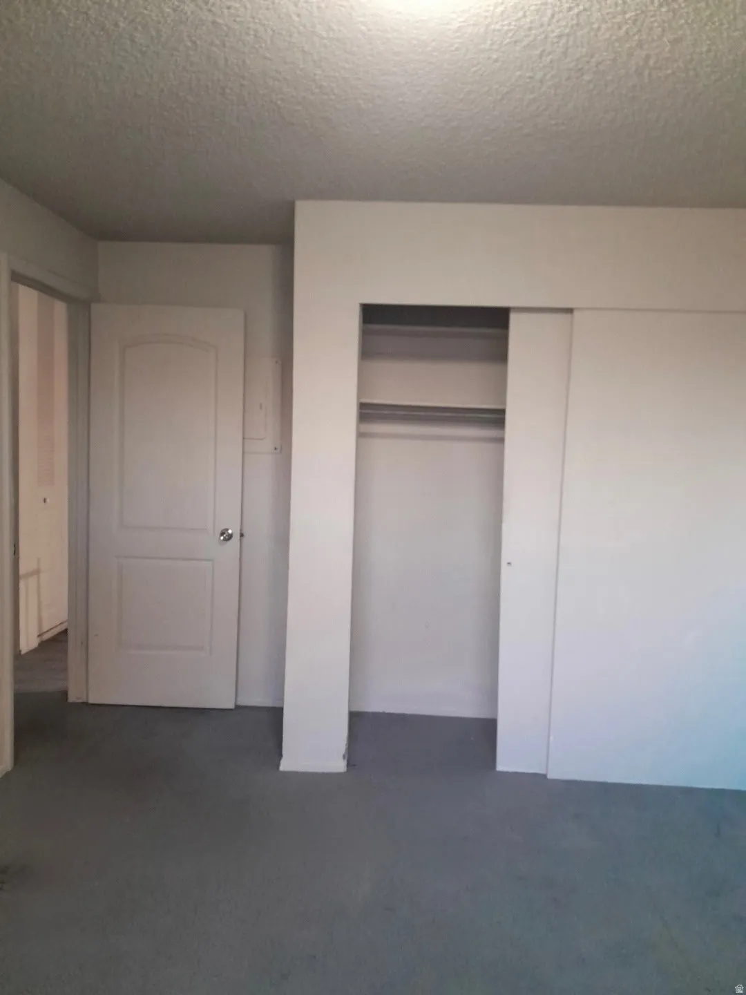 Bedroom featuring gray carpeting, white walls, and a built-in closet with sliding doors