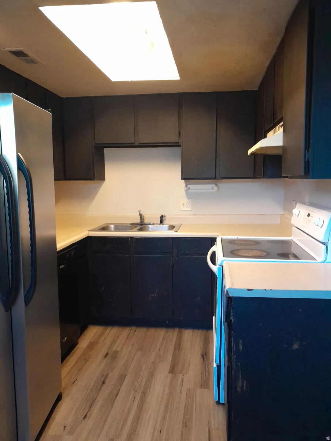 Kitchen featuring wood-finish flooring, dark cabinetry, and light-toned countertops