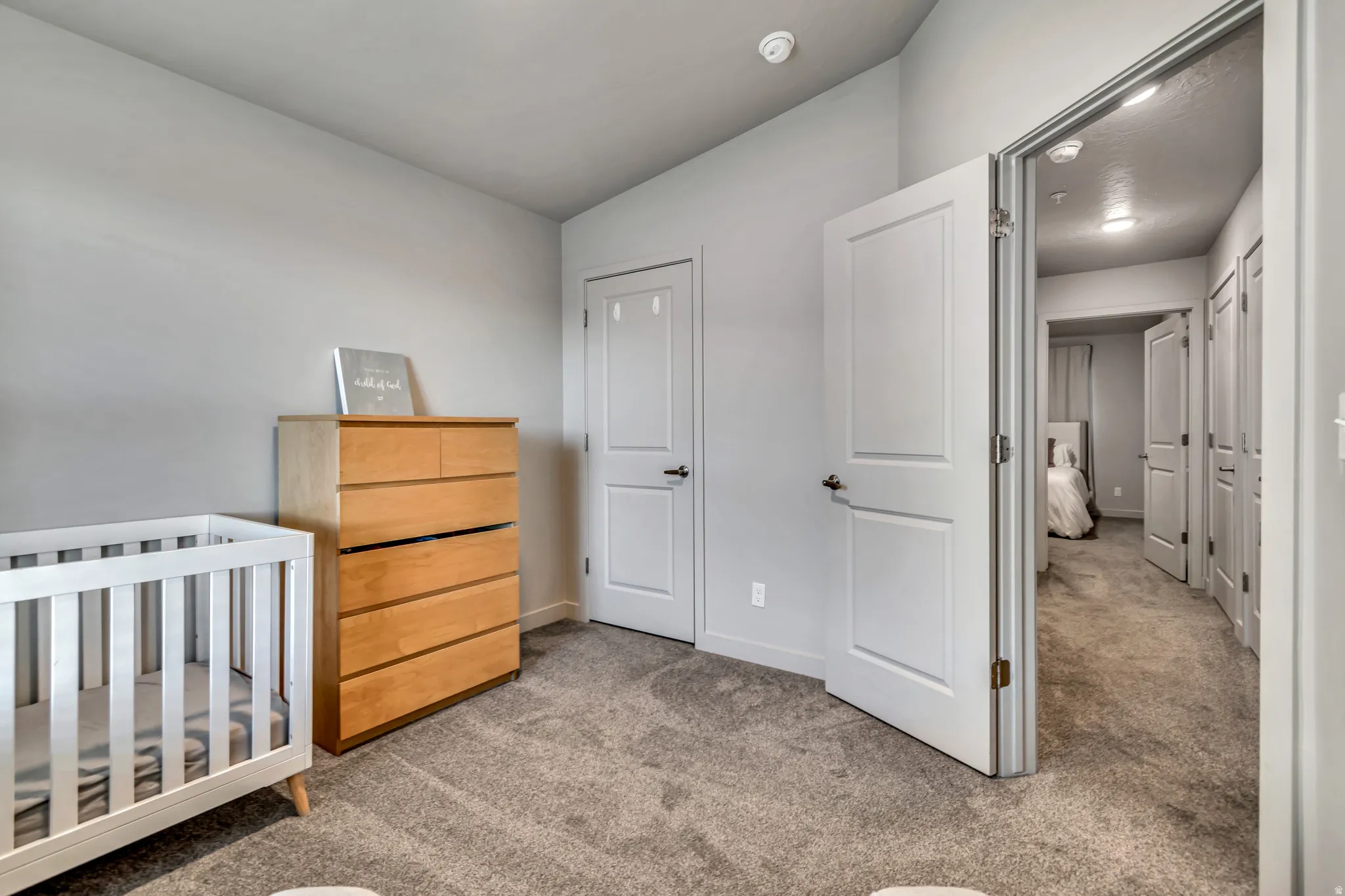 Carpeted room with light gray walls, white trim, and a white interior door